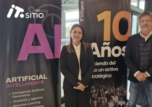 Dos personas del equipo de Taligent posando frente a banners de ITSitio sobre inteligencia artificial y los 10 años de la empresa